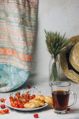 healthy light breakfast. sweet cherry with croissants on a plate. bouquet in a vase with spikelets of wheat. tea in a cup. Straw hat. proper nutrition for a slim figure. raw foods vegetarianism. diet