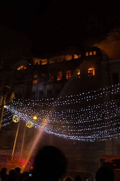 Fuego en las ventanas del antiguo edificio por la noche en invierno sobre el fondo de guirnaldas. extinción de incendios. Kiev, 20 de enero de 2018 —  Fotos de Stock