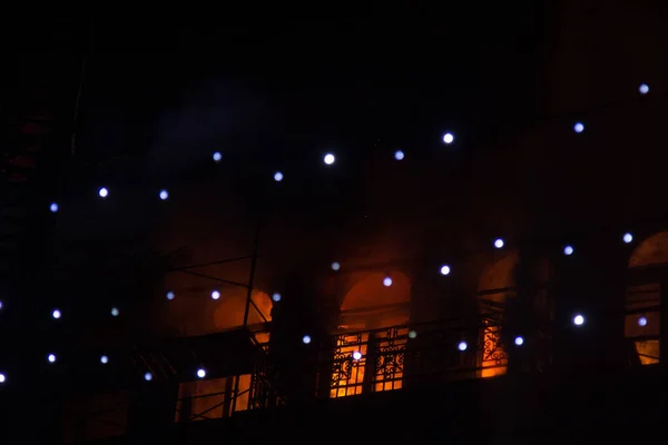 Φωτιά στα παράθυρα του παλιού κτηρίου τη νύχτα το χειμώνα με φόντο γιρλάντες. πυροσβεστικών πυρκαγιών. Κίεβο, 20 Ιανουαρίου, 2018 — Φωτογραφία Αρχείου