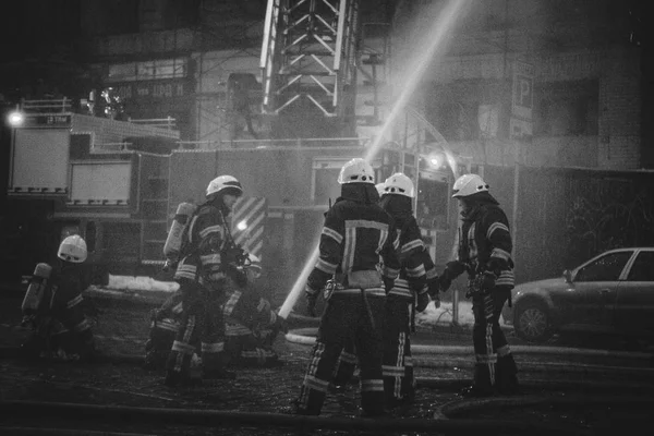 Bomberos en el trabajo. extinguiendo el agua de fuego en la noche de invierno. torre de bomberos, manguera de incendios. Kiev enero 20, 2018 —  Fotos de Stock