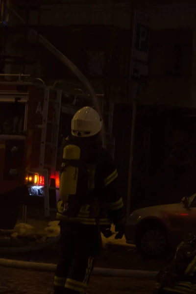 Bomberos en el trabajo. extinguiendo el agua de fuego en la noche de invierno. torre de bomberos, manguera de incendios. Kiev, 20 de enero de 2018 —  Fotos de Stock