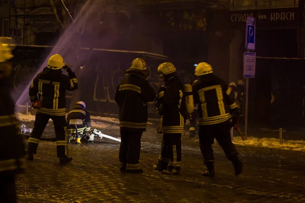 Bomberos en el trabajo. extinguiendo el agua de fuego en la noche de invierno. torre de bomberos, manguera de incendios. Kiev, 20 de enero de 2018 —  Fotos de Stock