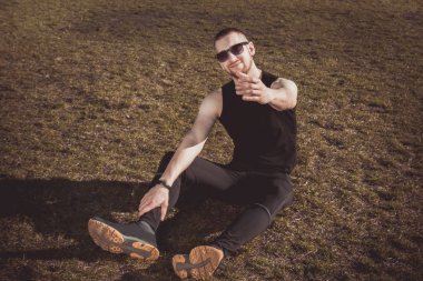 Stadyumdaki idmandan sonra spor giyimli genç adam çimlerin üzerinde dinleniyor. eğitimden sonra iyileşme