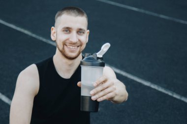 stadyumda eğitim kas ince adam bir spor shaker su içiyor. rekreasyon sporları. atletik egzersiz