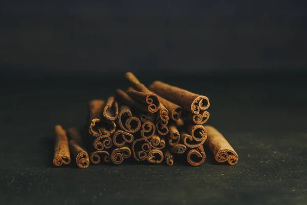 Un montón de palos enteros de canela fragante en una mesa rural de madera. espacio de copia. composición de condimentos y especias aromáticas de saborización de diapositivas. Primer plano. vista frontal — Foto de Stock