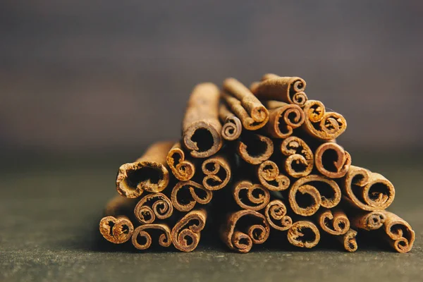 Un montón de palos enteros de canela fragante en una mesa rural de madera. espacio de copia. composición de condimentos y especias aromáticas de saborización de diapositivas. Primer plano. vista frontal — Foto de Stock