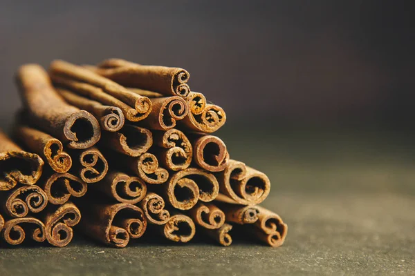 Un montón de palos enteros de canela fragante en una mesa rural de madera. espacio de copia. composición de condimentos y especias aromáticas de saborización de diapositivas. Primer plano. vista frontal — Foto de Stock