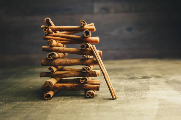 Torre de palos enteros de canela fragante sobre una mesa rural de madera. espacio de copia. composición de condimentos y especias aromáticas de saborización de diapositivas. Primer plano. vista lateral, macro — Foto de Stock