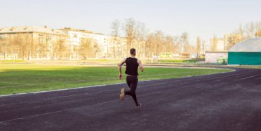Beyaz bir erkek sprint başlangıcı yapıyor. bir lastik yolda stadyumüzerinde çalışan. Spor üniformalı atletizm koşucusu. enerjik fiziksel aktiviteler. açık hava egzersiz, sağlıklı yaşam tarzı