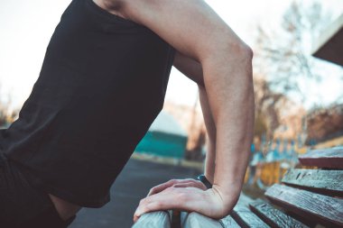 Siyah elbiseli genç bir adam açık havada yakın egzersiz. spor alanında fitness sporcusu. mermi ile eğitim. yaz için vücut hazırlığı ısınmak