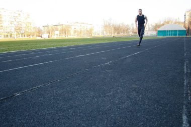 Beyaz bir erkek sprint başlangıcı yapıyor. kauçuk yolda çalışıyor. Spor üniformalı atletizm koşucusu. enerjik fiziksel aktiviteler. açık hava egzersiz, sağlıklı yaşam tarzı