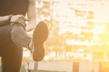 Siyah elbiseli bir adam açık havada bariyerli egzersiz yapmaktır. spor alanında fitness sporcusu. engel ile eğitim. bacaklar germe kadar ısınmak. yaz için vücut hazırlığı