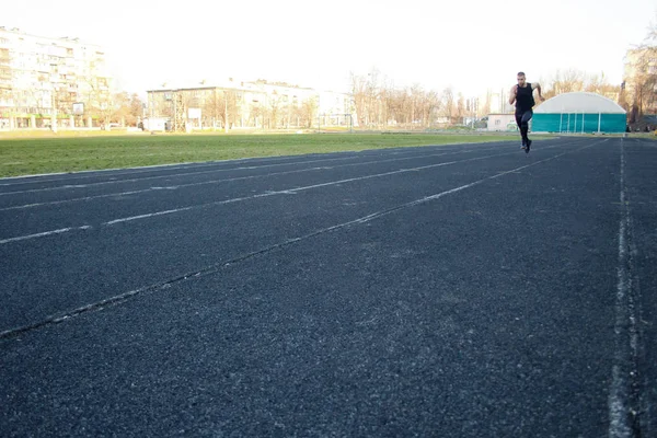 Jeden Kavkazský samec začíná ve sprintu. na gumových kolejích. Trať a polní běžec ve sportovní uniformě. energickou fyzickou aktivitu. venkovní cvičení, zdravý životní styl — Stock fotografie