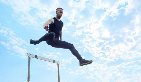 one caucasian male in a jump over a barrier. running on the stadium. Track and field runner in sport uniform in flight. energetic physical activities. outdoor exercise, healthy lifestyle. hurdling