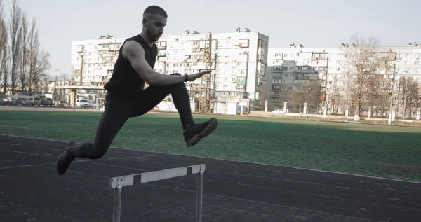 Bir bariyerin üzerinden atlayan beyaz bir erkek. stadyumda çalışıyor. Uçuş spor üniforması atletizm koşucusu. enerjik fiziksel aktiviteler. açık hava egzersiz, sağlıklı yaşam tarzı. engelli — Stok fotoğraf