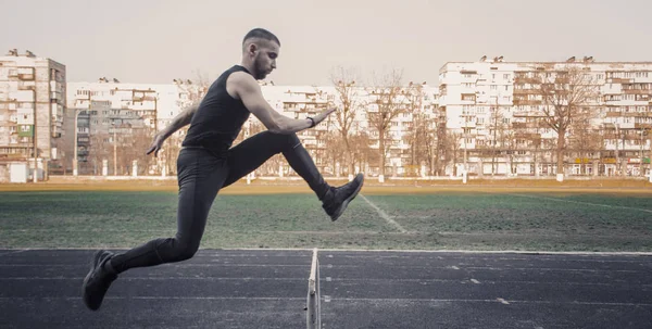 Bir bariyerin üzerinden atlayan beyaz bir erkek. stadyumda çalışıyor. Uçuş spor üniforması atletizm koşucusu. enerjik fiziksel aktiviteler. açık hava egzersiz, sağlıklı yaşam tarzı. engelli — Stok fotoğraf