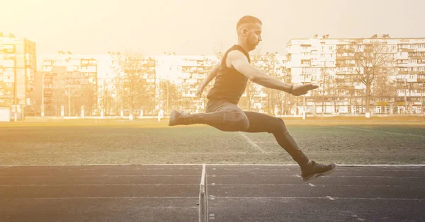 one caucasian male in a jump over a barrier. running on the stadium. Track and field runner in sport uniform in flight. energetic physical activities. outdoor exercise, healthy lifestyle. hurdling