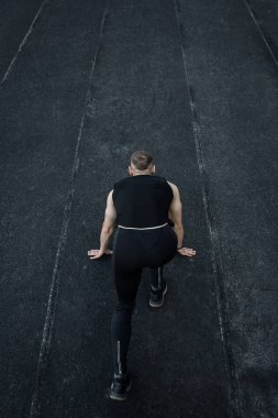 kafkas adam bir sprint başlangıç yapıyor. bir parça üzerinde stadyum üzerinde çalışan. Spor üniformalı atletizm koşucusu. enerjik fiziksel aktiviteler. açık hava egzersiz, sağlıklı yaşam tarzı. dikey üst görünüm