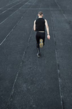 kafkas adam bir sprint başlangıç yapıyor. bir parça üzerinde stadyum üzerinde çalışan. Spor üniformalı atletizm koşucusu. enerjik fiziksel aktiviteler. açık hava egzersiz, sağlıklı yaşam tarzı. dikey üst görünüm