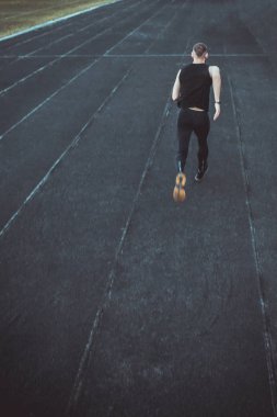 kafkas adam bir sprint başlangıç yapıyor. bir parça üzerinde stadyum üzerinde çalışan. Spor üniformalı atletizm koşucusu. enerjik fiziksel aktiviteler. açık hava egzersiz, sağlıklı yaşam tarzı. dikey üst görünüm