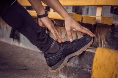 Siyah giyimli ince bir genç adam merdivenlerde açık havada egzersiz. fitness sporcusu. mermi ile eğitim. yaz için vücut hazırlık ısınmak. germe