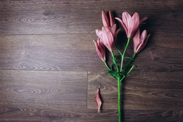 ahşap bir rustik masada ışık ışınları pembe zambak çiçek buketi. çiçekli bir bitki yakın çekim taze tomurcukları, kopya alanı, üst görünümü. stüdyo çekimi. tatil kartının arsa