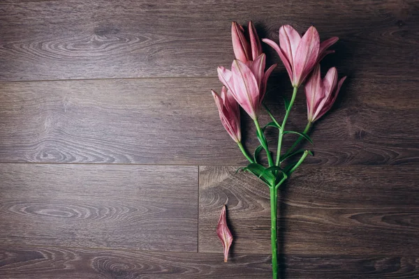 ahşap bir rustik masada ışık ışınları pembe zambak çiçek buketi. çiçekli bir bitki yakın çekim taze tomurcukları, kopya alanı, üst görünümü. stüdyo çekimi. tatil kartının arsa