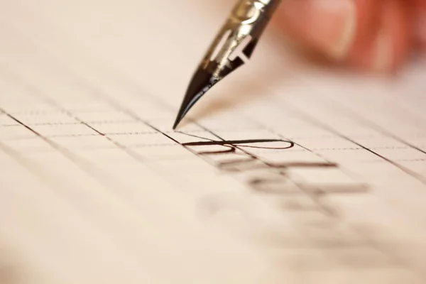 Main féminine écrit avec le stylo encré sur une feuille de papier blanc avec des rayures. papeterie sur bureau vue rapprochée sur le dessus. leçons d'orthographe et exercices de caligraphie. Modèle, disposition, arrière-plan. macro — Photo