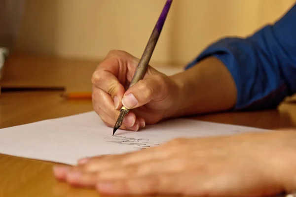 La mano femenina escribe con el bolígrafo de tinta en una hoja de papel blanco con rayas. papelería en el escritorio de cerca vista superior. lecciones de ortografía y ejercicios de caligrafía. Plantilla, diseño, fondo —  Fotos de Stock