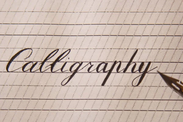 Kaligrafi beyaz kağıt bir sayfaya çizgili mürekkep kalemle yazılır. Kırtasiye üst görüntüyü kapatın. Heceleme dersleri ve kaligrafi alıştırmaları. Şablon, düzen, arka plan. makro