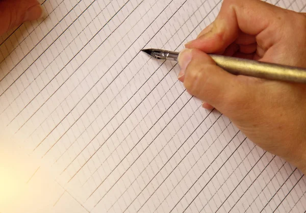 Mão feminina escreve com a caneta de tinta em folha de papel branco vazio com listras. artigos de papelaria na mesa de perto vista superior. aulas de ortografia e exercícios de caligrafia. Modelo, layout, fundo — Fotografia de Stock