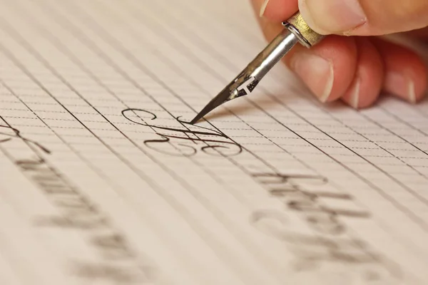 La mano femenina escribe con el bolígrafo de tinta en una hoja de papel blanco con rayas. papelería en el escritorio de cerca vista superior. lecciones de ortografía y ejercicios de caligrafía. Plantilla, diseño, fondo. macro —  Fotos de Stock