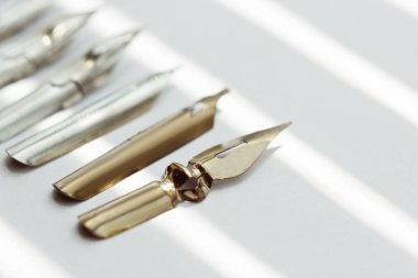 güneş ışınları beyaz bir arka plan üzerinde mürekkep kalem için metal ipuçları. beyaz masada kırtasiye üst görünümü kapatın. yazım dersleri ve kaligrafi egzersizleri. Şablon, düzen, arka plan. Makro