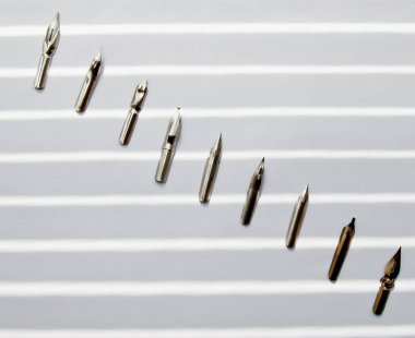 güneş ışınları beyaz bir arka plan üzerinde mürekkep kalem için metal ipuçları. beyaz masada kırtasiye üst görünümü kapatın. yazım dersleri ve kaligrafi egzersizleri. Şablon, düzen, arka plan. Makro