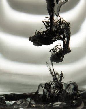 ışık ışınları ile çizgili bir ekranın arka planında açık su ile şeffaf bir cam bardak mürekkep bulutu. Şablon, düzen, arka plan, doku. makro difüzyon siyah beyaz