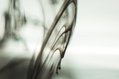 ışık ışınları arasında berrak su ile şeffaf bir cam bardak mürekkep bulutu. Şablon, düzen, arka plan, doku. makro difüzyon siyah beyaz soyutlama