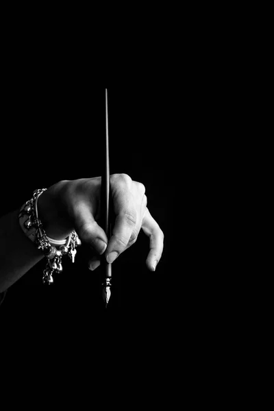 Female hand elegantly holding an ink pen with a metal tip close-up on a black background. classic fountain pen isolated macro black and white. copy space. vertical — Stock Photo, Image