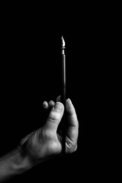 Mano femminile elegantemente tenendo una penna a inchiostro con una punta di metallo primo piano su uno sfondo nero. penna stilografica classica isolato macro bianco e nero. copiare spazio. verticale — Foto Stock