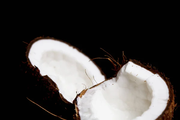 Zralý kokosový ořech je rozdělen na dvě poloviny izolovaná na černém pozadí zblízka. vnitřnosti tropického palmového plodu — Stock fotografie