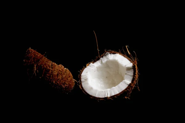 O coco maduro é dividido em duas metades isoladas em um fundo preto close-up. as entranhas do feto tropical de palma — Fotografia de Stock