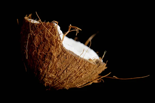 Zralý kokosový ořech je rozdělen na dvě poloviny izolovaná na černém pozadí zblízka. vnitřnosti tropického palmového plodu — Stock fotografie