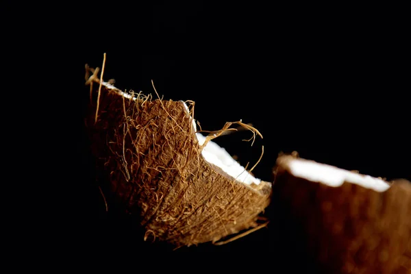Dojrzały orzech kokosowy jest podzielony na dwie połówki izolowane na czarnym tle zbliżenie. z wnętrza tropikalnego płód dłoni — Zdjęcie stockowe