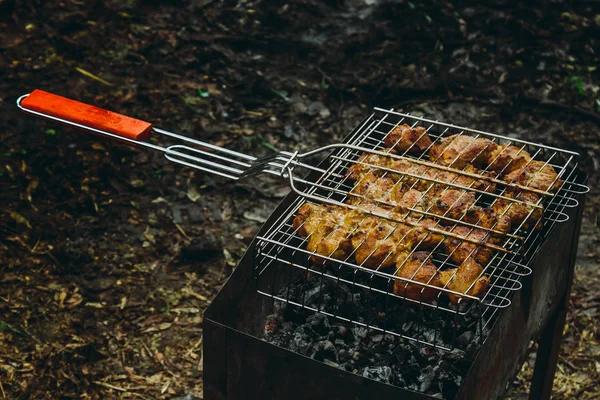 Cubes de viande marinée dans une grille de gril au brasero. kebab barbecue sur les braises à l'extérieur. pique-nique grillé dans la nature. vue de dessus gros plan — Photo
