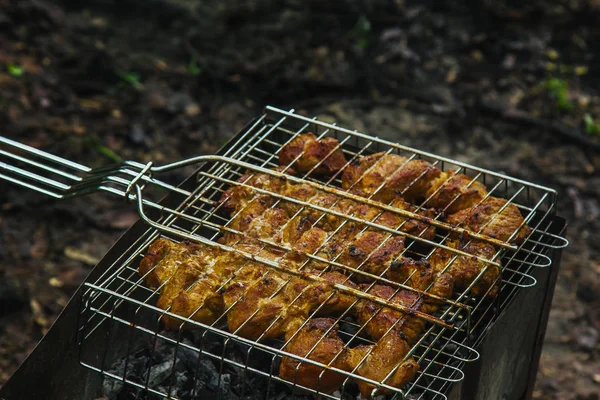 Würfel aus eingelegtem Fleisch in einem Grillrost am Kohlenbecken braten. Dönerspieße auf Glutnestern grillen. gegrilltes Picknick in der Natur. Ansicht von oben aus nächster Nähe — Stockfoto