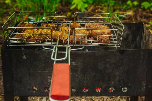 Würfel aus eingelegtem Fleisch in einem Grillrost am Kohlenbecken braten. Dönerspieße auf Glutnestern grillen. gegrilltes Picknick in der Natur. Ansicht von oben aus nächster Nähe — Stockfoto