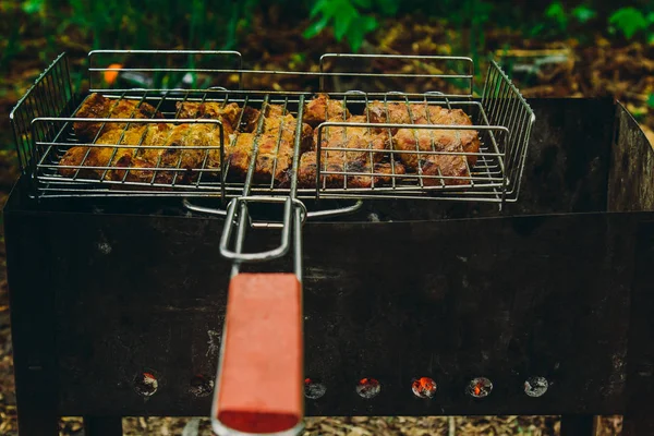 Cubes de viande marinée dans une grille de gril au brasero. kebab barbecue sur les braises à l'extérieur. pique-nique grillé dans la nature. vue de dessus gros plan — Photo