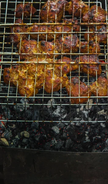 cubes of pickled meat in a grill grate at brazier. barbecue kebab on embers outdors. grilled picnic in nature. top view close up
