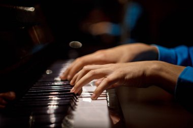 Piyanoda bir erkek el. Avuç içi tuşların üzerinde yer alır ve müzik okulunda klavyeli enstrüman çalar. öğrenci oynamayı öğrenir. eller piyanist. siyah koyu arka plan