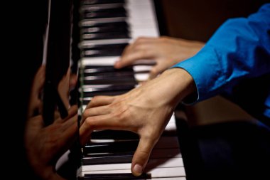 Piyanoda iki erkek eli. avuç içi tuşları çapraz yalan ve müzik okulunda klavye enstrüman çalmak. öğrenci oynamayı öğrenir. eller piyanist. siyah koyu arka plan. üst görünüm