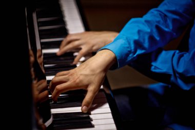 Piyanoda iki erkek eli. avuç içi tuşları çapraz yalan ve müzik okulunda klavye enstrüman çalmak. öğrenci oynamayı öğrenir. eller piyanist. siyah koyu arka plan. üst görünüm